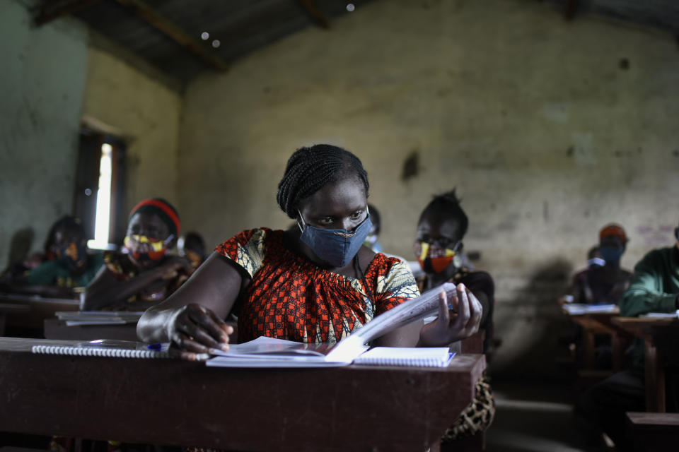 A trainee reads a handbook on coronavirus prevention, at a training session for community health workers conducted by the national NGO "Health Link" in Gumbo, on the outskirts of Juba, South Sudan Tuesday, Aug. 18, 2020. The coronavirus is exposing an uncomfortable inequality in the billion-dollar system that delivers life-saving aid to countries in crisis: Most money goes to international aid groups instead of local ones and now many local aid workers have been left exposed on the pandemic's front lines. (AP Photo/Charles Atiki Lomodong)