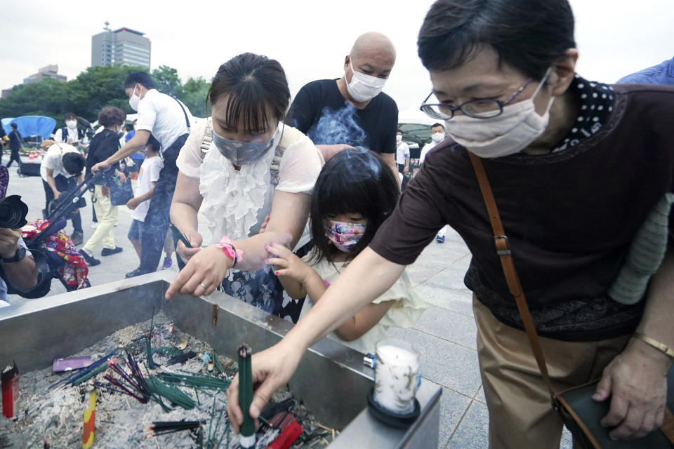 People burn joss sticks in front of the cenotaph for the atomic bombing victims before the start of a ceremony to mark the 75th anniversary of the U.S. bombing in Hiroshima, western Japan, early Thursday, Aug. 6, 2020. (AP Photo/Eugene Hoshiko)