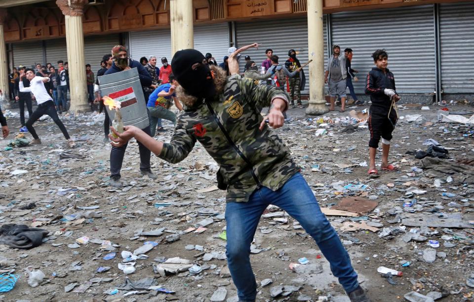 A anti-government protester prepares to throw a molotov cocktail toward security forces during clashes on Rasheed Street in Baghdad, Iraq, Thursday, Nov. 28, 2019. Anti-government protests have gripped Iraq since Oct. 1, when thousands took to the streets in Baghdad and the predominantly Shiite south. The largely leaderless movement is accusing the government of being hopelessly corrupt, and also decries Iran's growing influence in Iraqi state affairs. (AP Photo/Khalid Mohammed)