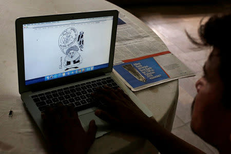 A man reads a newspaper's website with a cartoon depicting an alien creature, on a computer screen at a library in Karachi, Pakistan June 5, 2018. Picture taken June 5, 2018. REUTERS/Akhtar Soomro
