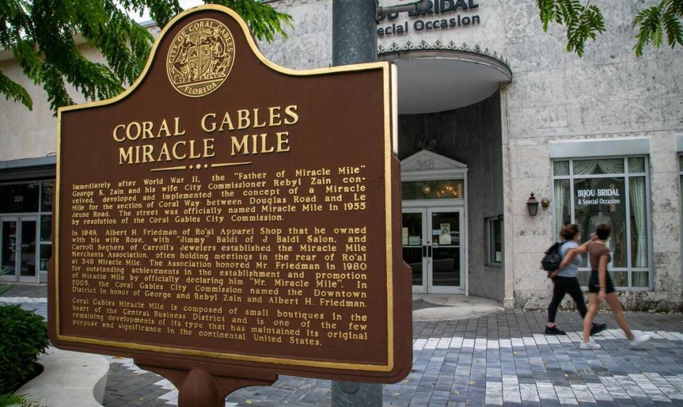 Coral Gables, Florida, Nov. 25, 2020: Pedestrians walk by a marker explaining the origins of Miracle Mile.