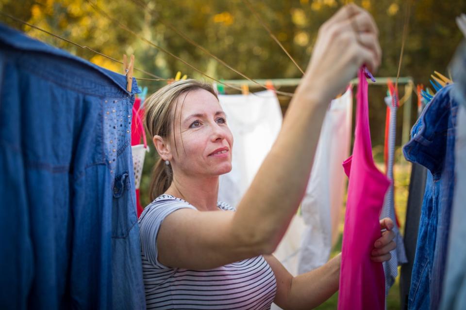 Woman hanging bright-colored clothing on clothesline outside