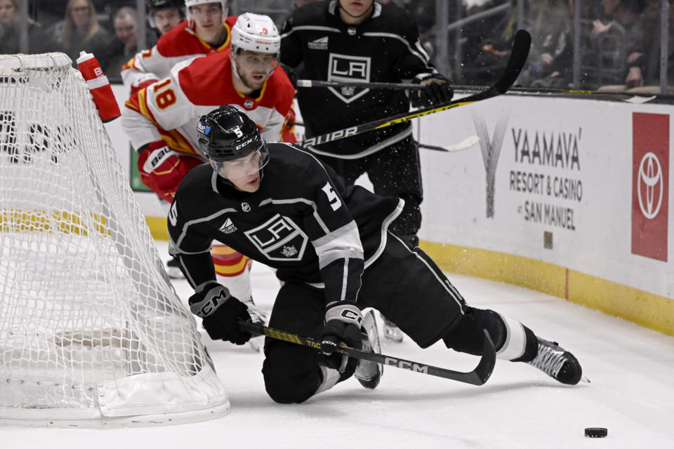 Los Angeles Kings defenseman Andreas Englund (5) protects the puck from Calgary Flames left wing A.J. Greer (18) during the third period of an NHL hockey game in Los Angeles, Saturday, Dec. 23, 2023. (AP Photo/Alex Gallardo)