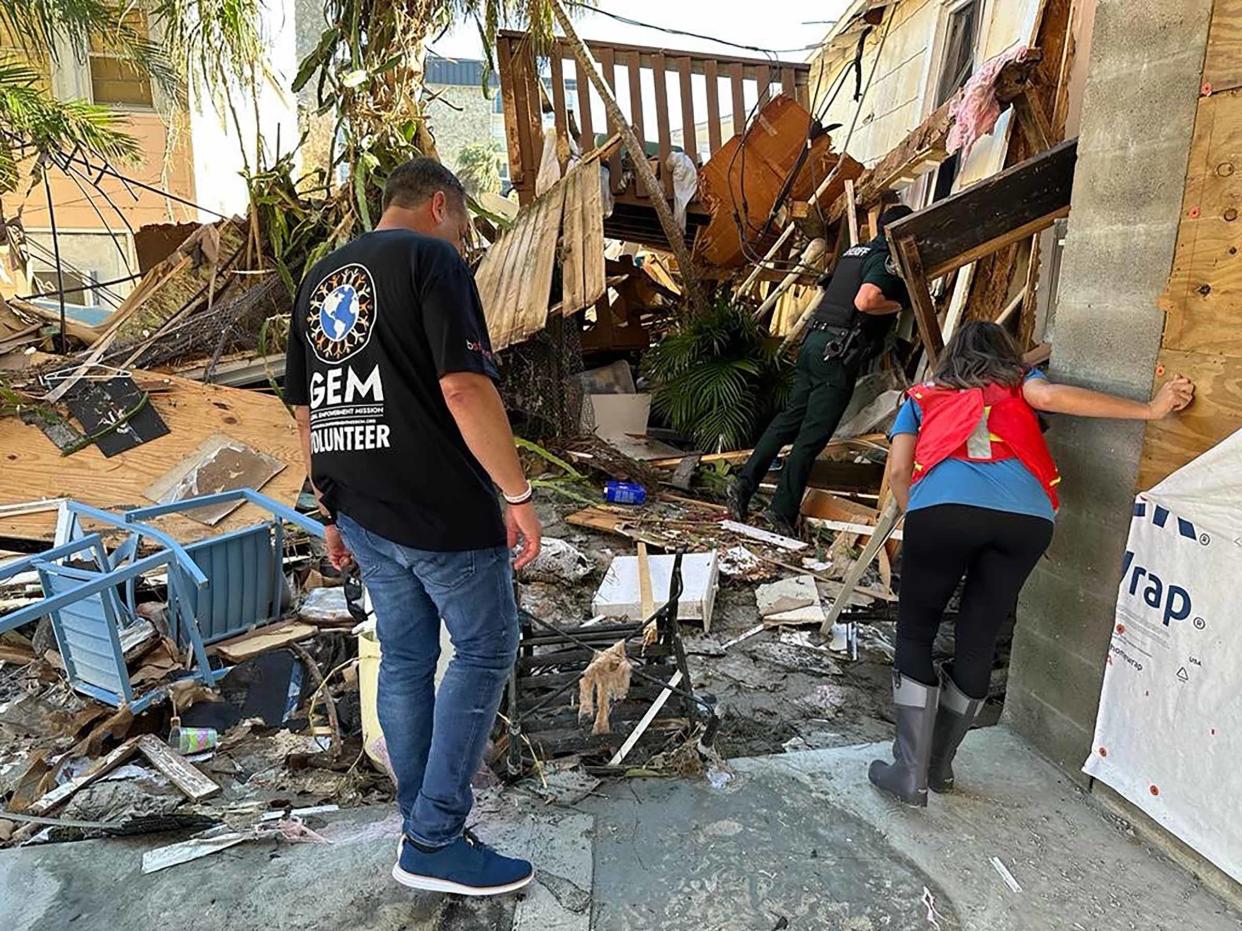 A volunteer wearing a T-shirt emblazoned with the logo for Global Empowerment Mission assists at a building damaged by Hurricane Ian. The organization is among the beneficiaries of donations raised through a fund established by the Town of Palm Beach United Way.