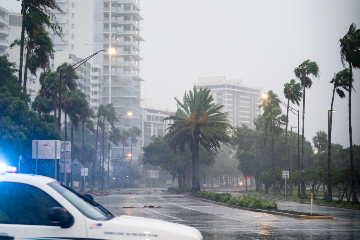 A police officer drives by an empty street as Hurricane Ian approaches on Sept. 28, 2022, in Sarasota, Fla. Forecasts call for the storm to make landfall today.