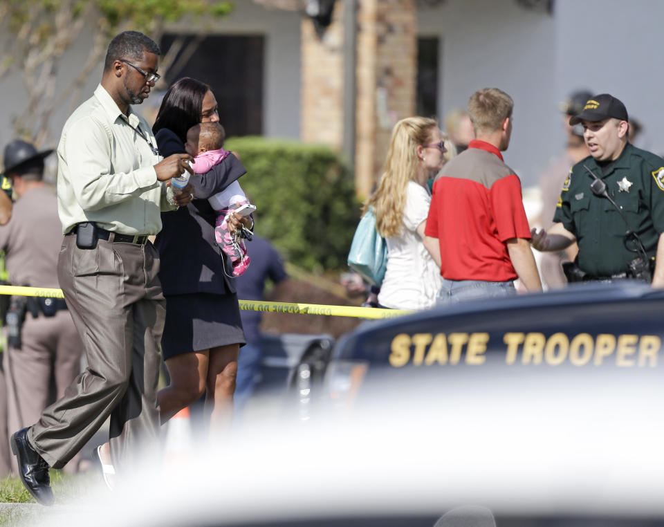 Parents leave a day care center with their children after a vehicle crashed into the center, Wednesday, April 9, 2014, in Winter Park, Fla. At least 15 people were injured, including children. (AP Photo/John Raoux)