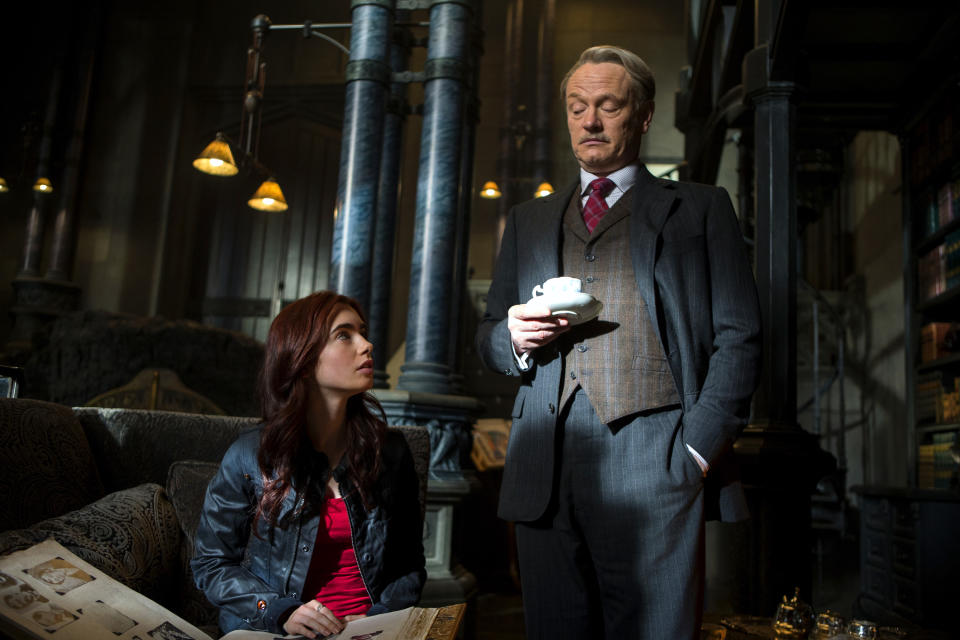 This film publicity image released by Screen Gems shows Lilly Collins as Clary, left, and Jared Harris as Hodge Starkweather in a scene from "The Mortal Instruments: City of Bones. (AP Photo/Sony Pictures Screen Gems, Rafy)