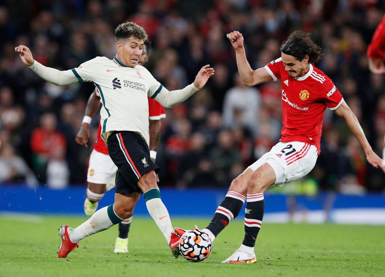 Liverpool's Roberto Firmino (left) tussles for the ball with Manchester United's Edinson Cavani. 