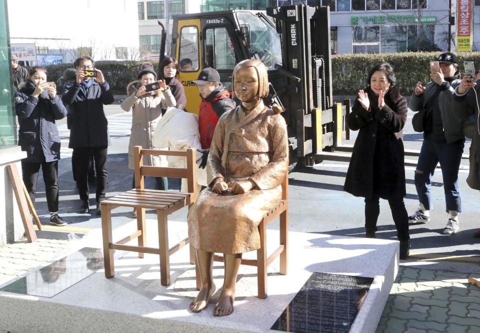 In this Dec. 30, 2016, photo, South Koreans take photos of a comfort-woman statue set up in front of the Japanese consulate in Busan, South Korea. Japan is recalling its ambassador to South Korea Friday, Jan. 6, 2017 in response to the placing of the statue. Many Koreans and other women in Asia were forced to work in brothels for the Japanese military during World War II in what was called the "comfort-woman" system. (Jo Jung-ho/Yonhap via AP)