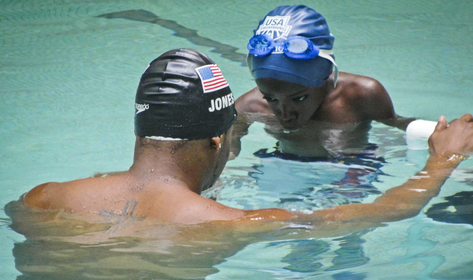 This May 17, 2013 photo released by Simone Smalls PR ahows, Olympic gold medalist Cullen Jones, left, teaching a breathing technique as he holds first grade student Malick Kane at Harlem's P.S. 125 pool in New York. Jones is ambassador for the 5th Annual USA Swimming Foundation's "Make a Splash Tour," providing free swimming lessons, water safety education and awareness at city pools. (AP Photo/Simone Smalls PR)