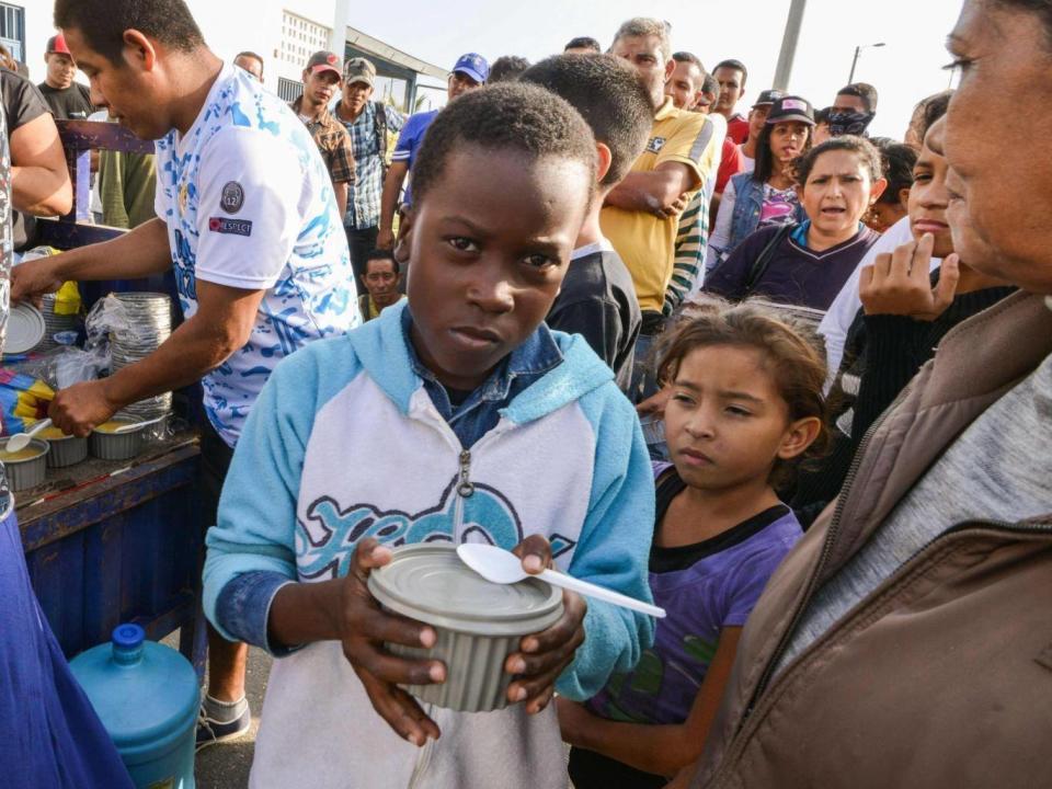 Venezuelan nationals receive food from religious volunteers while they wait for an authorisation that will allow them to enter Peru. (AFP/Getty Images)