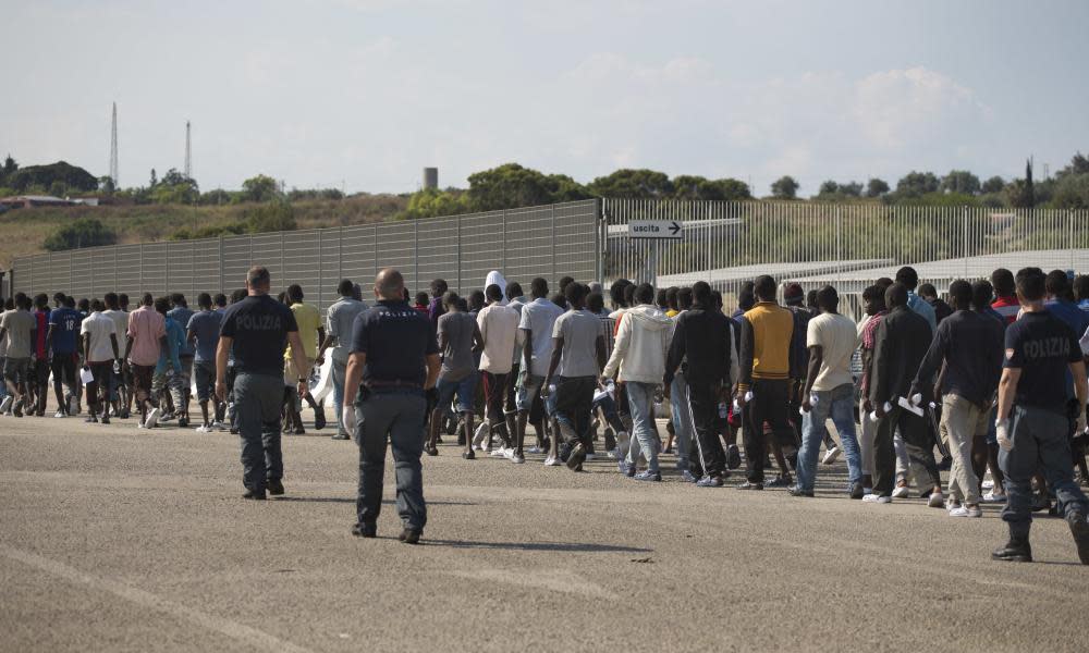 Italian border police with crowd of men