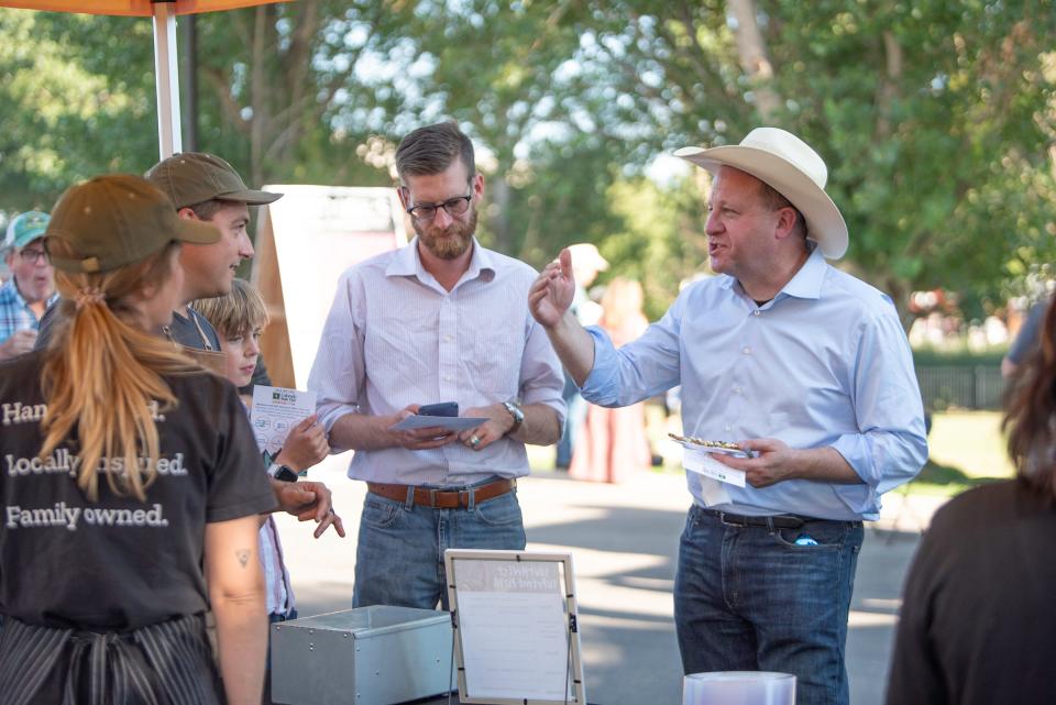 Gov. Jared Polis speaks with Wes and Bre Latka of Stoke Pizza during the Governor's Plate competition at the Colorado State Fair on Tuesday, August 29, 2023.