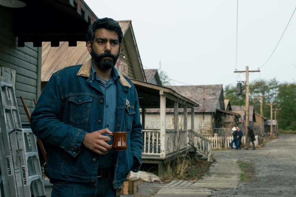 A man standing outside a home holding a mug