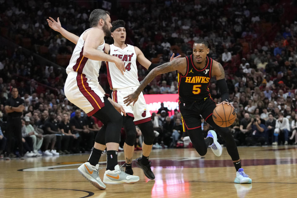 Atlanta Hawks guard Dejounte Murray (5) drives to the basket as Miami Heat forward Kevin Love, left, and guard Tyler Herro (14) defend during the first half of an NBA basketball game Friday, Dec. 22, 2023, in Miami. (AP Photo/Lynne Sladky)