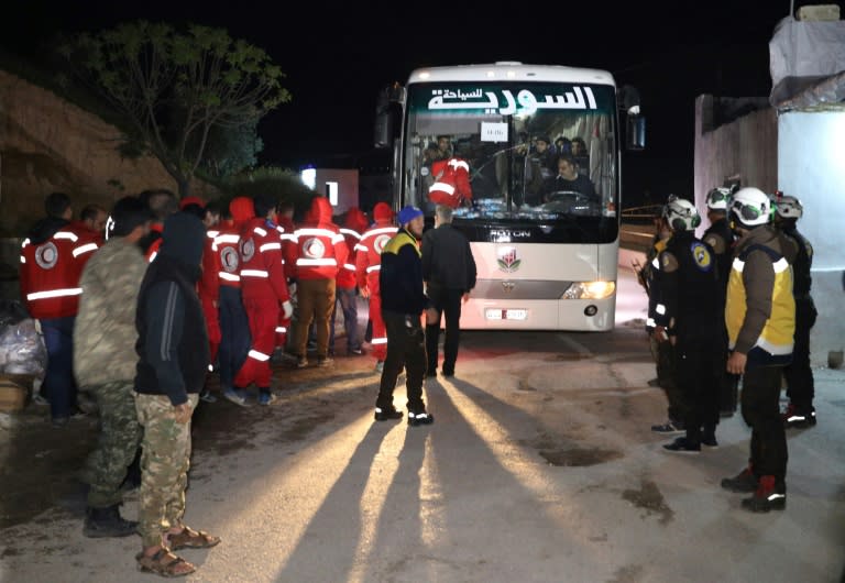 A first convoy evacuating rebel fighters and their families from the Eastern Ghouta enclave outside Damascus reaches the Hama province town of Qalaat al-Madiq where rebels and Red Crescent and White Helmets members await them early on March 23, 2018