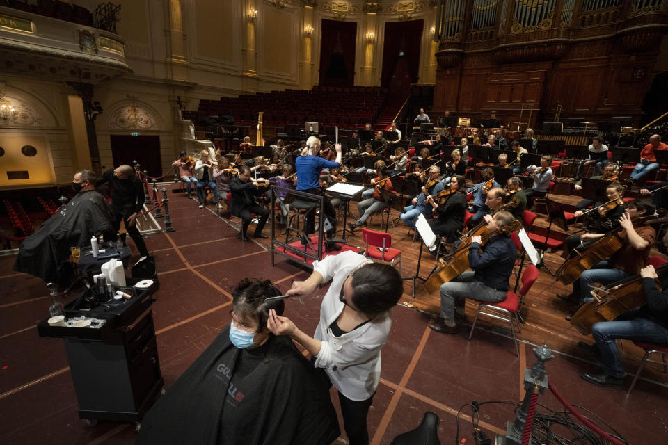 People get a haircut on stage during a rehearsal at the Concertgebouw in Amsterdam, Wednesday, Jan. 19, 2022, as Dutch museums, theaters and concert halls played host Wednesday to businesses that are allowed to open to customers as a protest against their own continuing lockdown closures. (AP Photo/Peter Dejong)