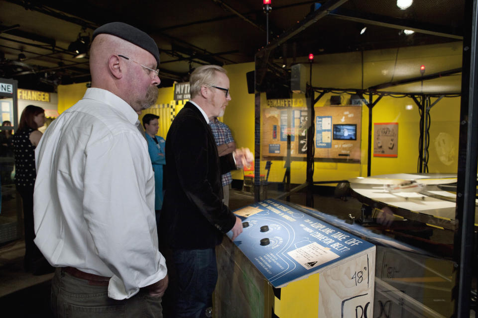 In this March 14, 2012 photo provided by the Museum of Science and Industry, Jamie Hyneman, left, and Adam Savage, stars of the Discovery Channel television show "Mythbusters" check out an exhibit on whether or not an airplane could take off from a conveyor belt going in the opposite direction at the same rate of speed during a media preview for "MythBusters: The Explosive Exhibition," modeled after the show at the Museum of Science and Industry in Chicago. The exhibit opens Thursday, March 15 and runs through Sept. 3. The planned national tour that will include stops at several other U.S. cities. (AP Photo/Museum of Science and Industry, J.B. Spector)