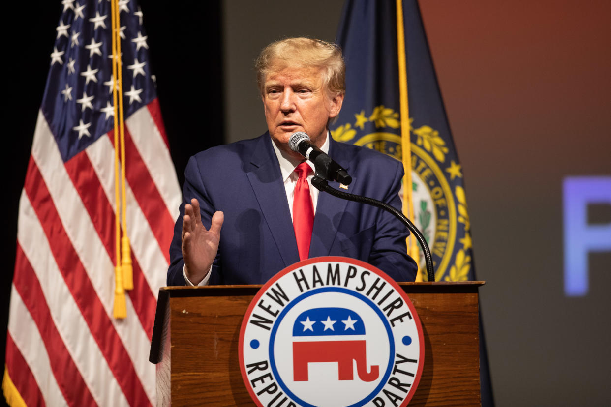 Former President Donald Trump speaks at a podium marked New Hampshire Republican Party, in front of an American flag and the state flag.