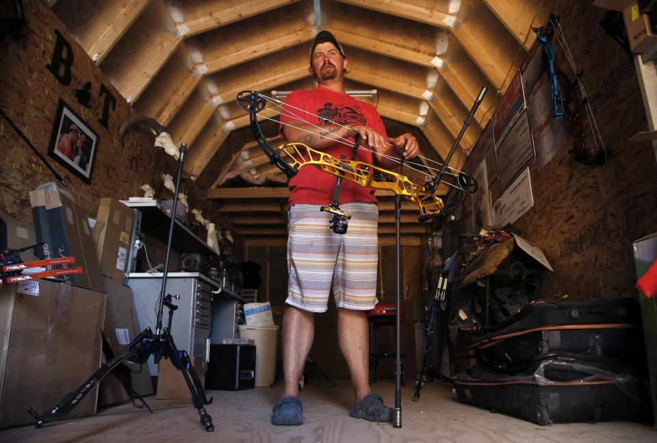 FILE - In this April 30, 2020, file photo, U.S. Olympic Team archer Brady Ellison pauses with a compound bow at his range on his farm in Miami, Ariz. The playbook for athletes provides a guide to a "safe and successful Games" for the Tokyo Olympics. It's filled with "cannots" and "do nots," meaning a once-in-a-liftetime opportunity will be a whole lot less fun. (AP Photo/Ross D. Franklin, File)