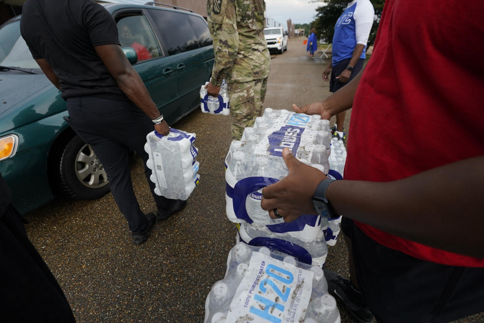 Volunteers distribute cases of water at a community/fraternal drive-thru water distribution site in Jackson, Miss., Sept. 7, 2022. A boil-water advisory has been lifted for Mississippi's capital, and the state will stop handing out free bottled water on Saturday. But the crisis isn't over. Water pressure still hasn't been fully restored in Jackson, and some residents say their tap water still comes out looking dirty and smelling like sewage. (AP Photo/Rogelio V. Solis)