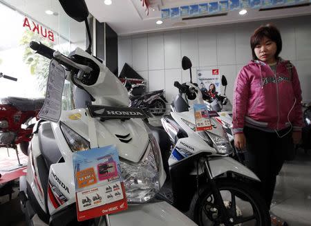 A customer looks at a Honda Beat (L) motorcycle at a Honda showroom in Jakarta, November 19, 2014. REUTERS/Pius Erlangga