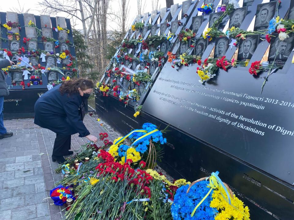 A Ukrainian woman places flowers at a memorial for those killed in the 2014 Revolution of Dignity. / Credit: Haley Ott / CBS News