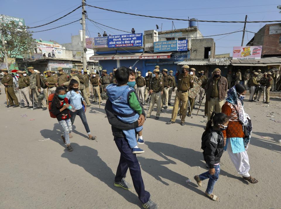 Commuters walk with their children after police seal the Haryana-New Delhi border to block protesting farmers from marching to the capital in New Delhi, India, Thursday, Nov.26, 2020. The farmer's have been protesting against the federal agriculture laws. (AP Photo/Manish Swarup)