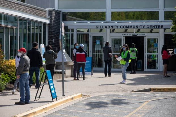 People line up outside the Killarney Community Centre to receive a COVID-19 vaccination in Vancouver. (Ben Nelms/CBC - image credit)