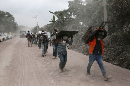 People carry stuff at an area affected by the eruption of the Fuego volcano in the community of San Miguel Los Lotes in Escuintla, Guatemala June 5, 2018. REUTERS/Luis Echeverria