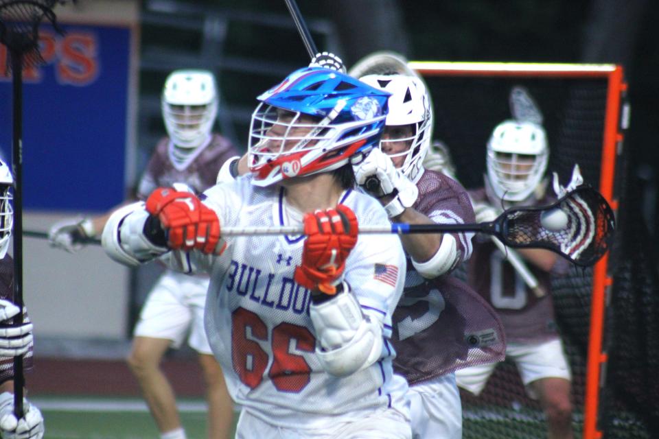 Bolles attacker Daylin John-Hill (66) attempts to pass under pressure from Oak Hall long-stick midfielder Miles Sims (25) during Saturday night's game.