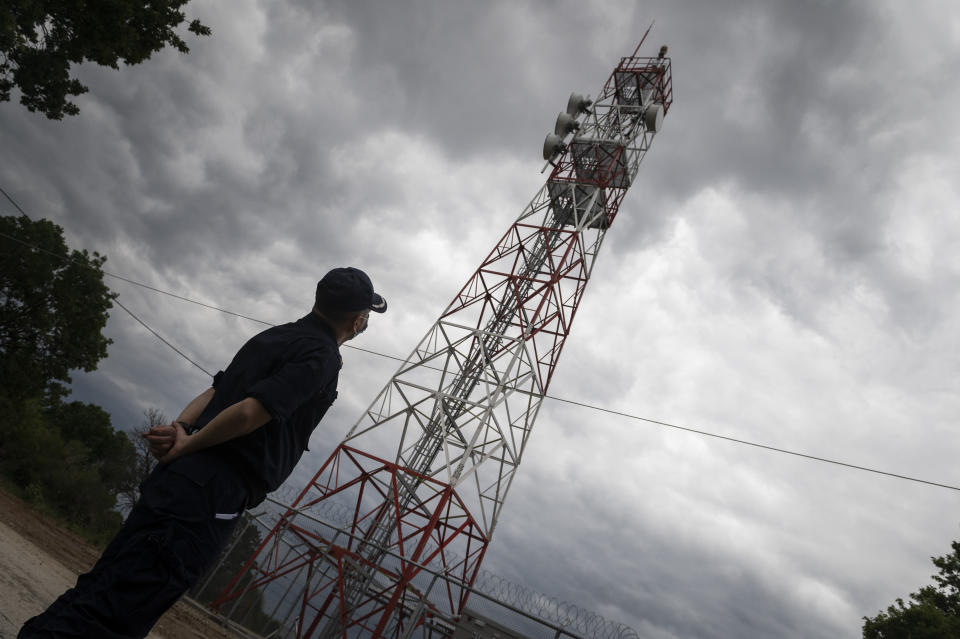 Police officer Dimosthenis Kamargios watches an electronic surveillance tower near the village of Lagyna, at the Greek -Turkish border, Greece, Friday, May 21, 2021. An automated hi-tech surveillance network being built on the Greek-Turkish border aiming at detecting migrants early and deterring them from crossing, with river and land patrols using searchlights and long-range acoustic devices. (AP Photo/Giannis Papanikos)