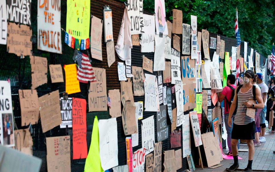 A demonstrator reads messages left in front of the White House's recently erected security fence now turned into a memorial against police brutality and the death of George Floyd - AFP