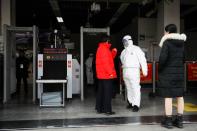 A worker in protective suit speaks with people at the entrance of the Xizhimen subway station, as the country is hit by an outbreak of the new coronavirus, in Beijing