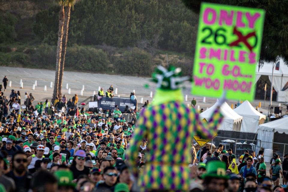 A man holds a sign reading "Only 26.2 Smiles To Go" at the L.A. Marathon.