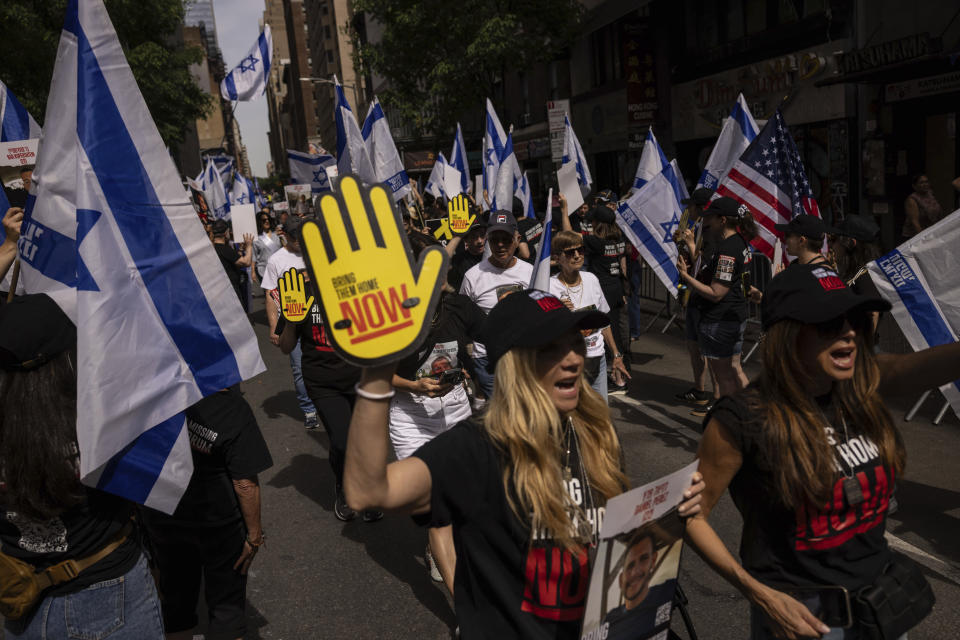 People hold Israeli flags and signs ahead of the annual Israel Day Parade on Sunday, June 2, 2024, in New York. (AP Photo/Yuki Iwamura)