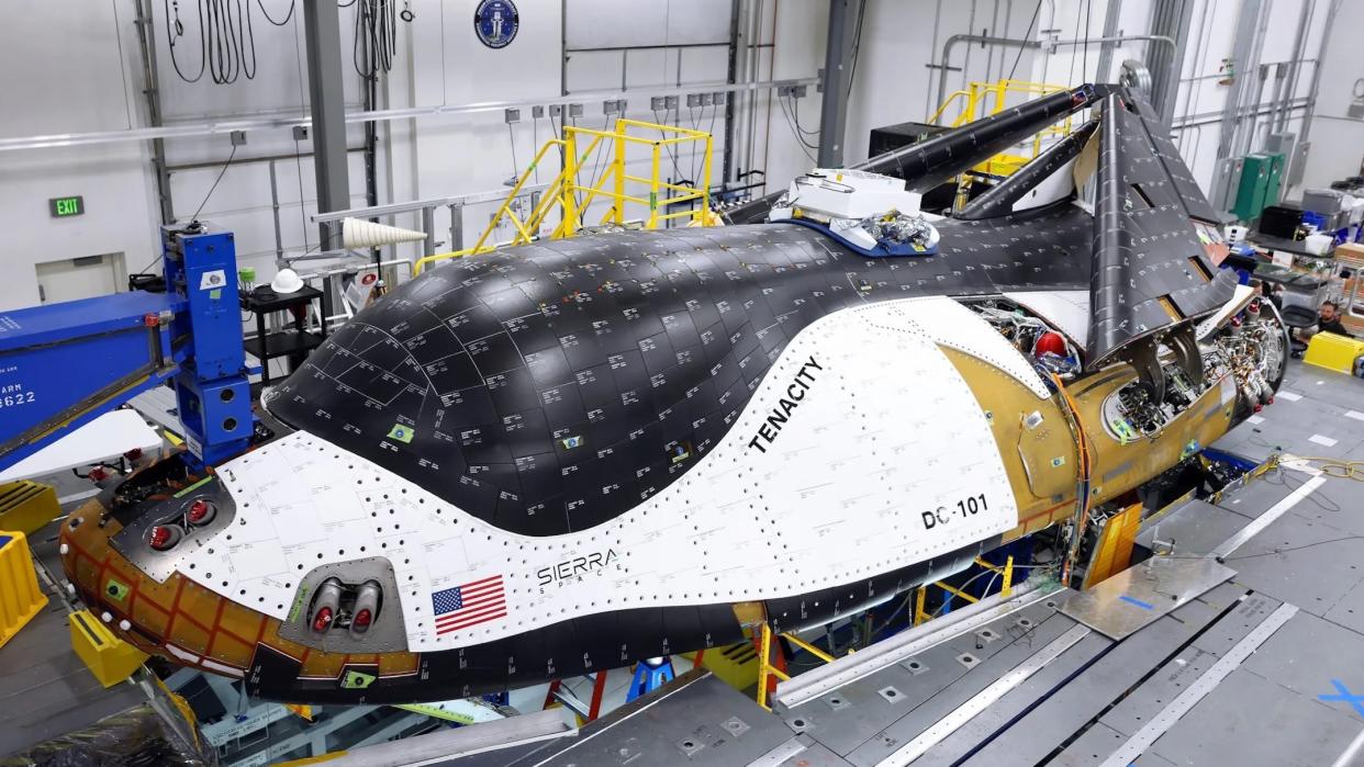  A white and black robotic space plane inside a hangar. 