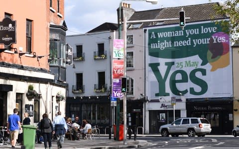 Pedestrians pass a giant poster urging a 'yes' vote in the referendum - Credit: AFP