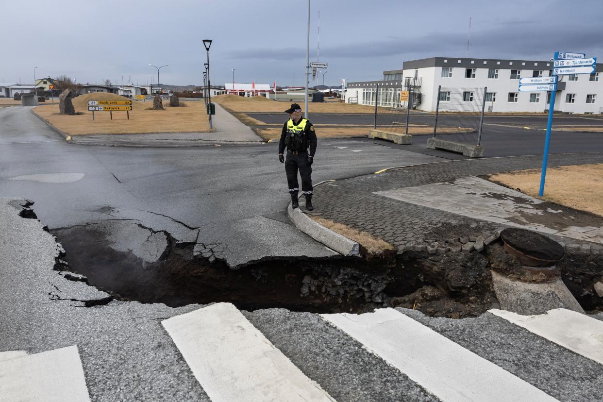 A police officer stands by the crack in a road in the fishing town of Grindavik which was evacuated due to volcanic activity (REUTERS)