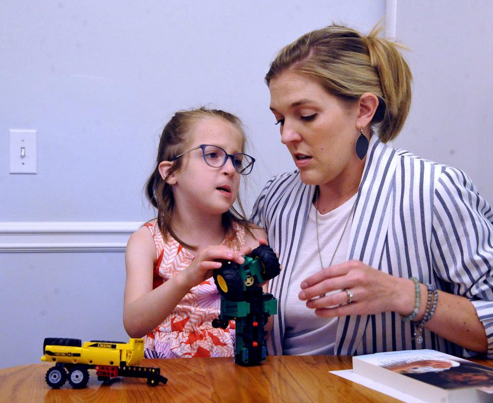 Charlotte Whiting works with some toys to keep her busy as she listens to her mom, Emily, talk about her life.