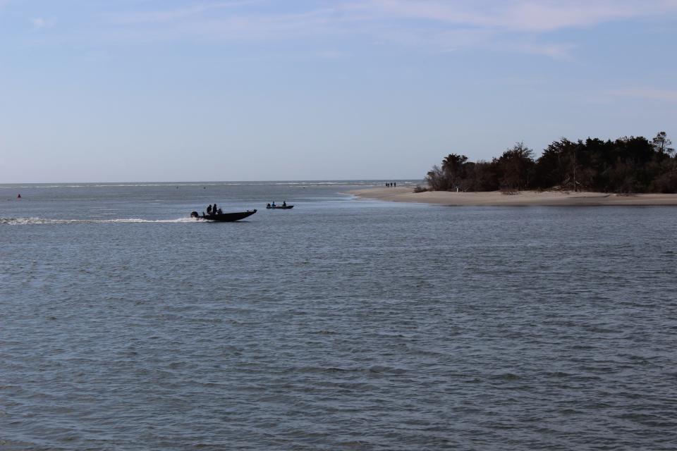 Small boats sit in the shallow waters off Holden Beach on Friday, March 17, 2023.