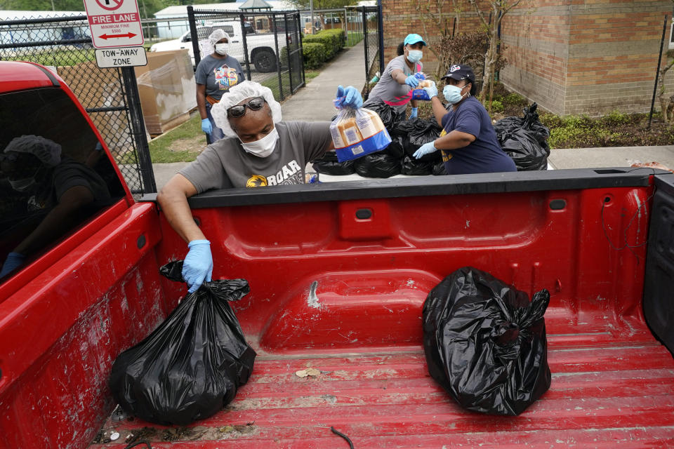 Houston Independent School District Nutrition Services workers load food into a pickup truck Monday, April 6, 2020, in Houston. HISD relaunched their food distribution efforts throughout the district Monday, with a streamlined process that will implement increased safety measures. (AP Photo/David J. Phillip)
