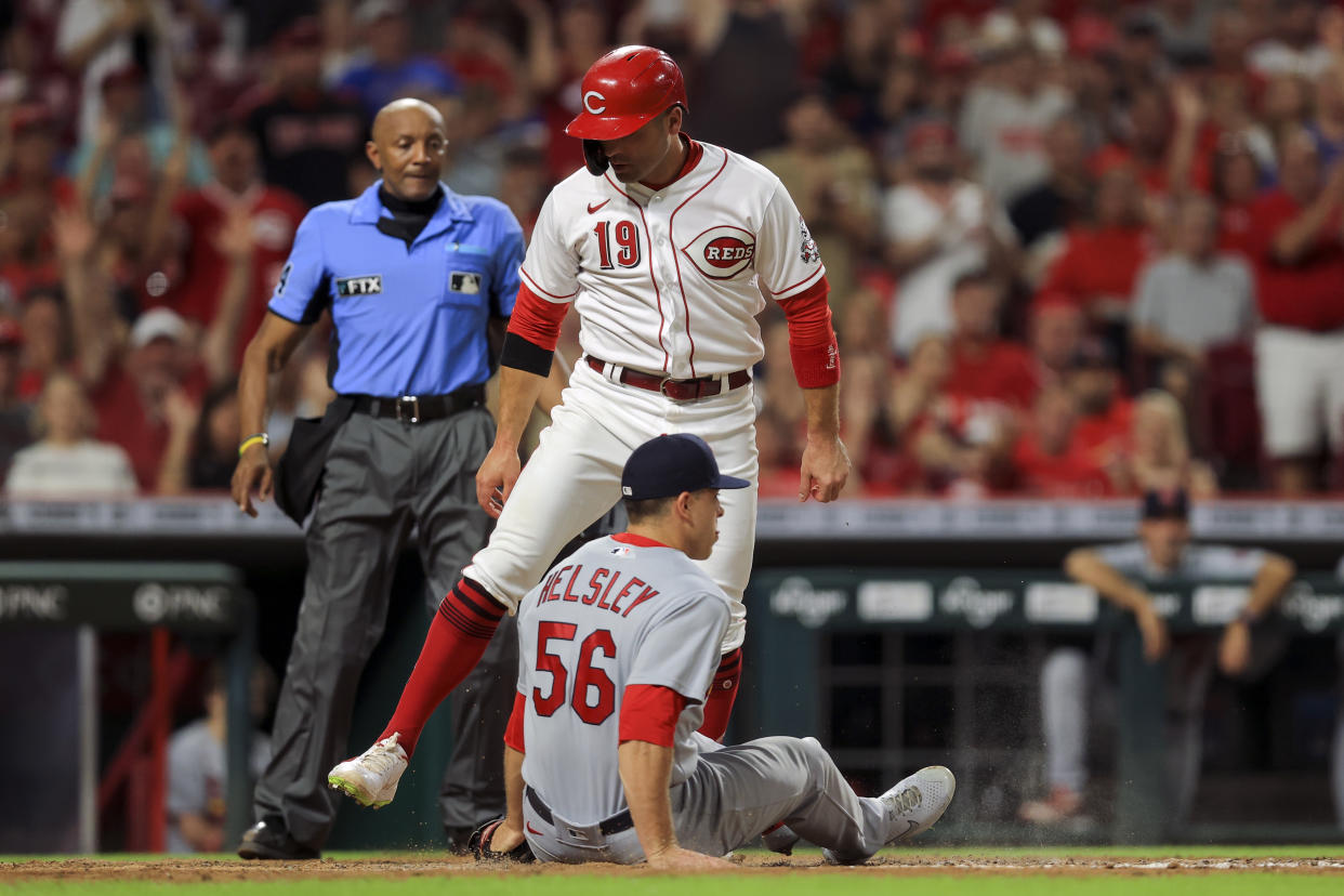 Cincinnati Reds' Joey Votto (19) scores a run on a wild pitch as St. Louis Cardinals' Ryan Helsley fields the ball during the seventh inning of a baseball game in Cincinnati, Friday, July 23, 2021. (AP Photo/Aaron Doster)