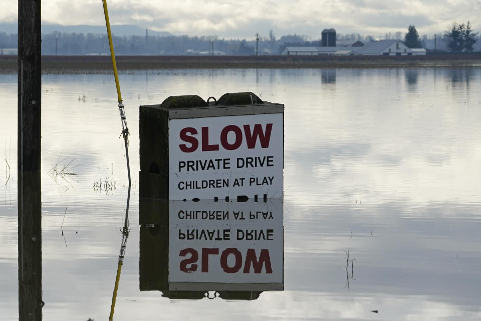 A partially submerged sign is shown near a flooded farm field near Sumas, Wash., Monday, Nov. 29, 2021. People in Sumas, located near the Canadian border, were asked to evacuate voluntarily Saturday night, as communities in the area were still dealing with flooding from a storm earlier in the month. (AP Photo/Elaine Thompson)