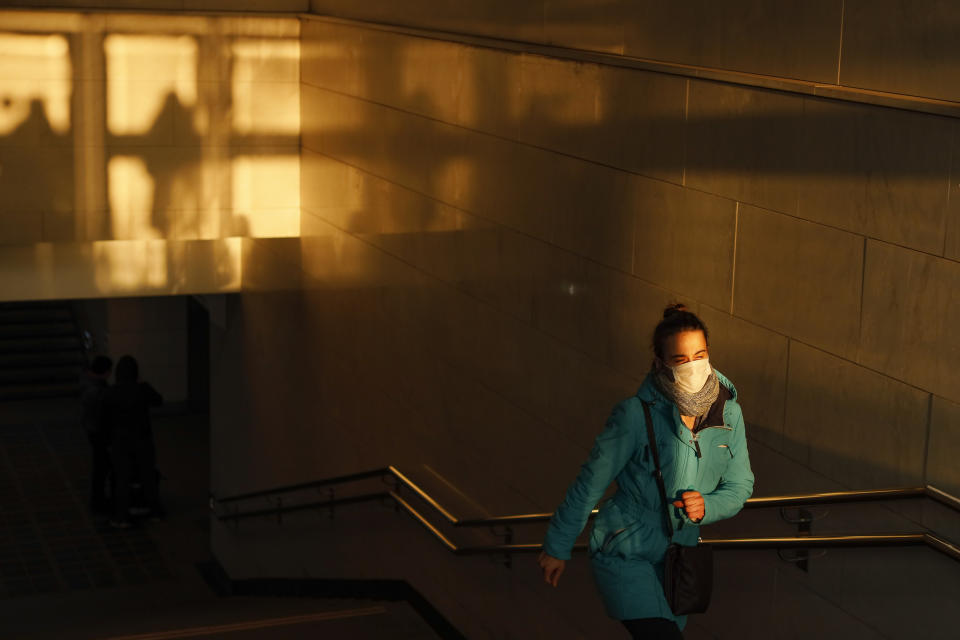A woman wearing a face mask to help curb the spread of the coronavirus walks from the underpass up to the street during sunset in Moscow, Russia, Wednesday, Dec. 2, 2020. Russia has registered a record number of coronavirus deaths for a second straight day. Currently, there is a country-wide mask mandate and mostly mild restrictions that vary from region to region. (AP Photo/Alexander Zemlianichenko)