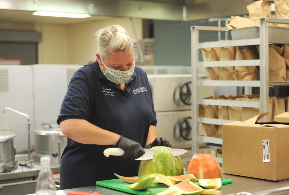 A food service worker makes a free meal at Sandwich High School, in a 2020 photo. Federal funds for universal free meals end with this school year, but the state Legislature may renew the program.