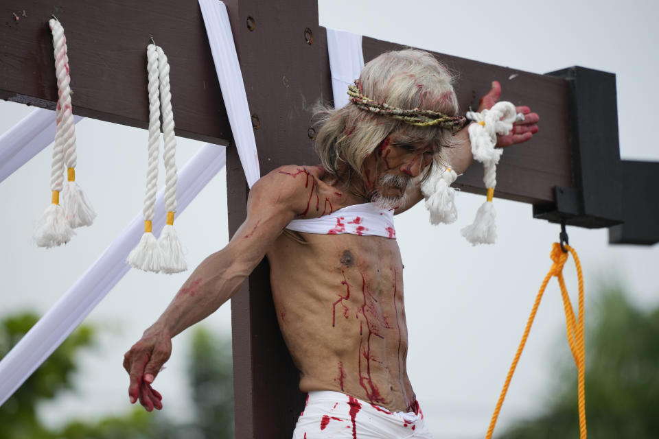 Wilfredo Salvador hangs on the cross during a reenactment of Jesus Christ's sufferings as part of Good Friday rituals April 7, 2023 in the village of San Pedro, Cutud, Pampanga province, northern Philippines. The real-life crucifixions, a gory Good Friday tradition that is rejected by the Catholic church, resumes in this farming village after a three-year pause due to the coronavirus pandemic.(AP Photo/Aaron Favila)