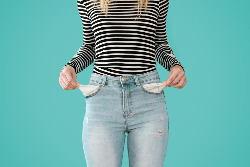 a woman pulling out her pockets from her jeans