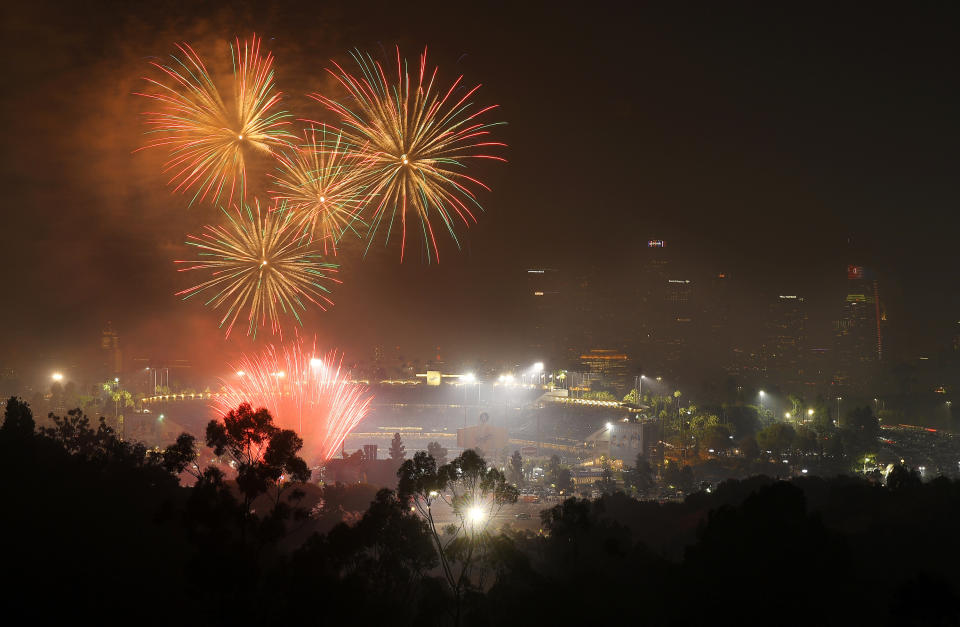 FILE - In this July 4, 2019, file photo, fireworks explode over Dodger Stadium with the Los Angeles skyline in the background following a baseball game between the Los Angeles Dodgers and the San Diego Padres in Los Angeles. With fewer professional celebrations on July 4, 2020, many Americans are bound to shoot off fireworks in backyards and at block parties. And they already are: Sales have been booming. (AP Photo/Mark J. Terrill, File)