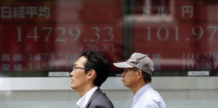 Men walk past electronic boards showing Japan's Nikkei average (L) and the exchange rate between the Japanese yen and the U.S. dollar, outside a brokerage in Tokyo May 27, 2014. REUTERS/Toru Hanai